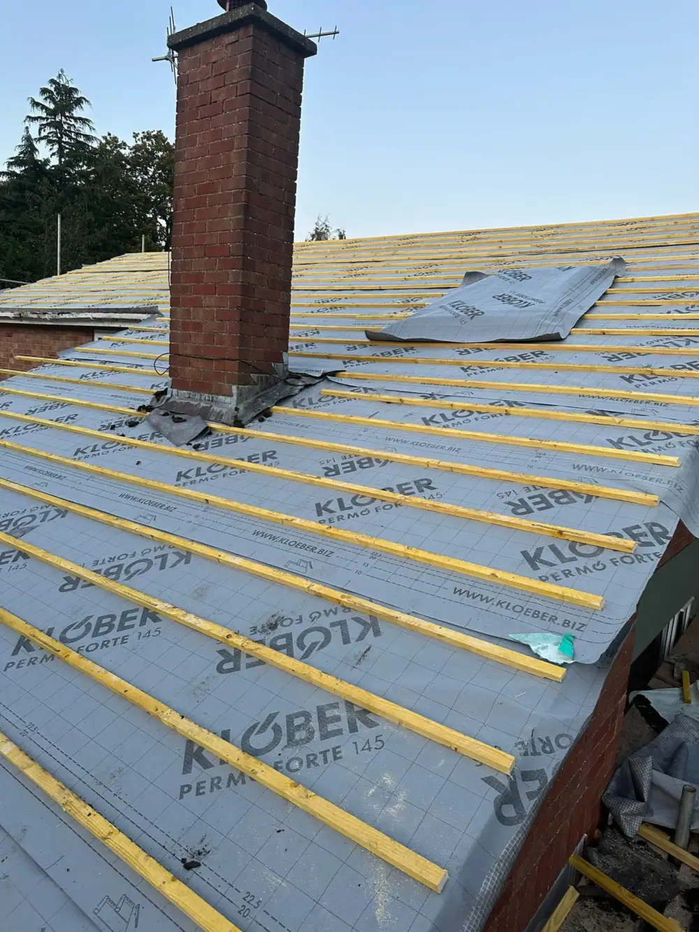 Roofers in Potters Bar: new membrane and battens fitted around a brick chimney