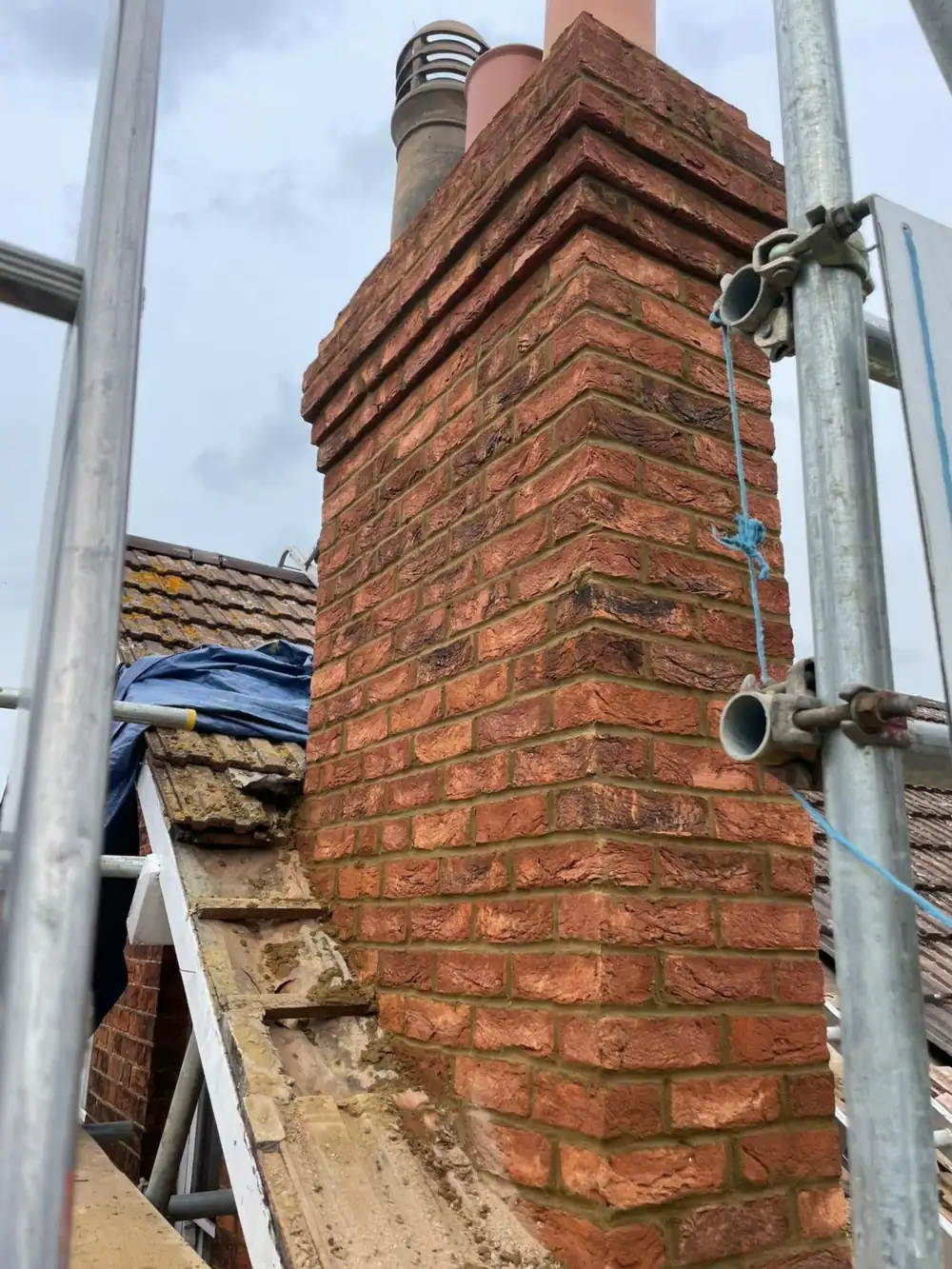 Tall brick chimney stack with scaffold before repair