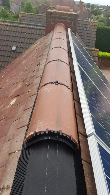 Dry ridge line on a finished tiled roof beside solar panels