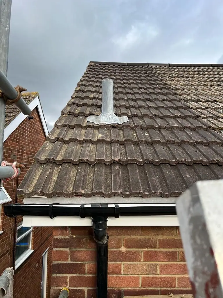 Finished tiled roof over a bay with a new vent pipe and new black guttering