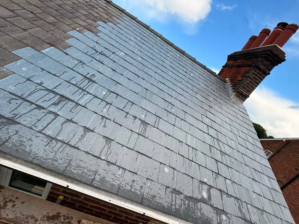 Finished slate roof and chimney against a blue sky
