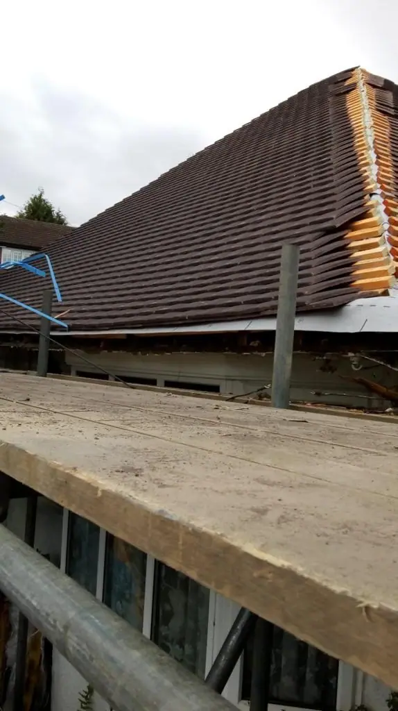 Hipped roof being tiled from the scaffold, a roof form common on garden city houses
