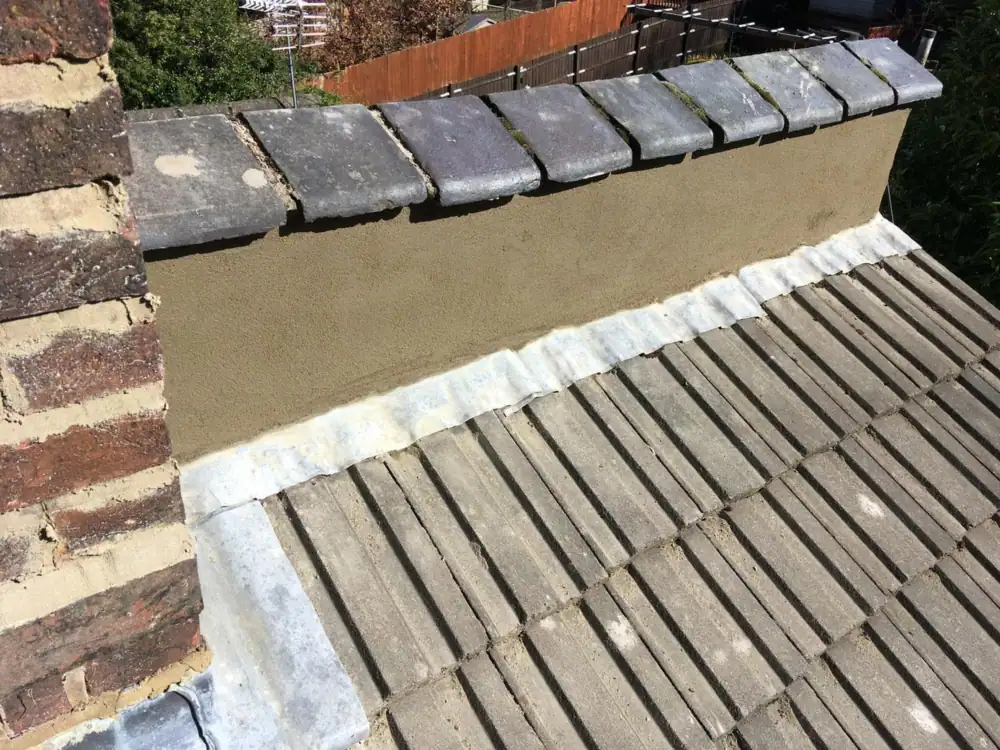 New lead flashing at a parapet wall above concrete tiles