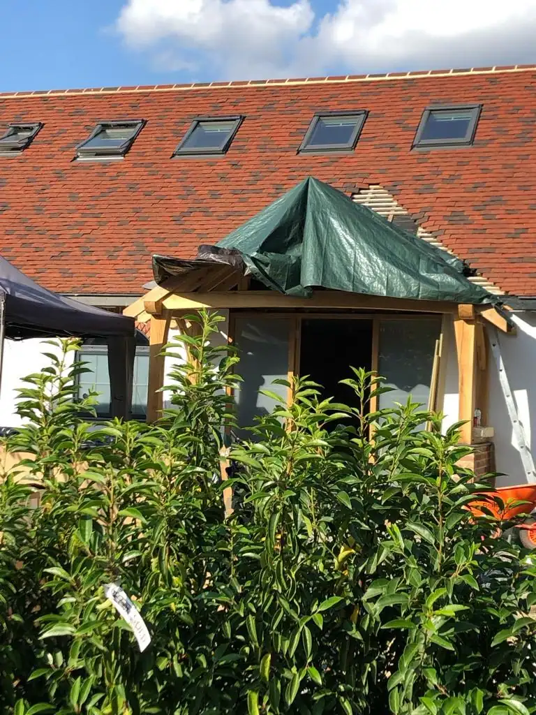 Roofers in Wembley: new red tile roof with a row of roof windows above a timber porch
