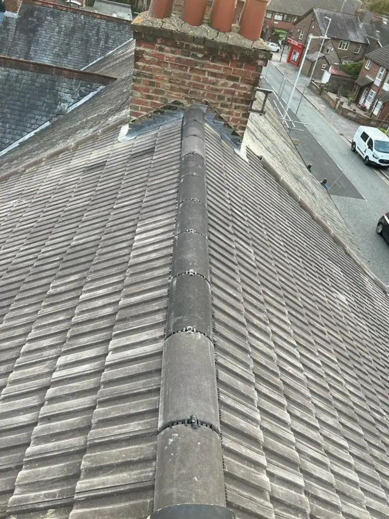 Roofing guarantee: new ridge line and chimney on a finished tiled roof with the street below