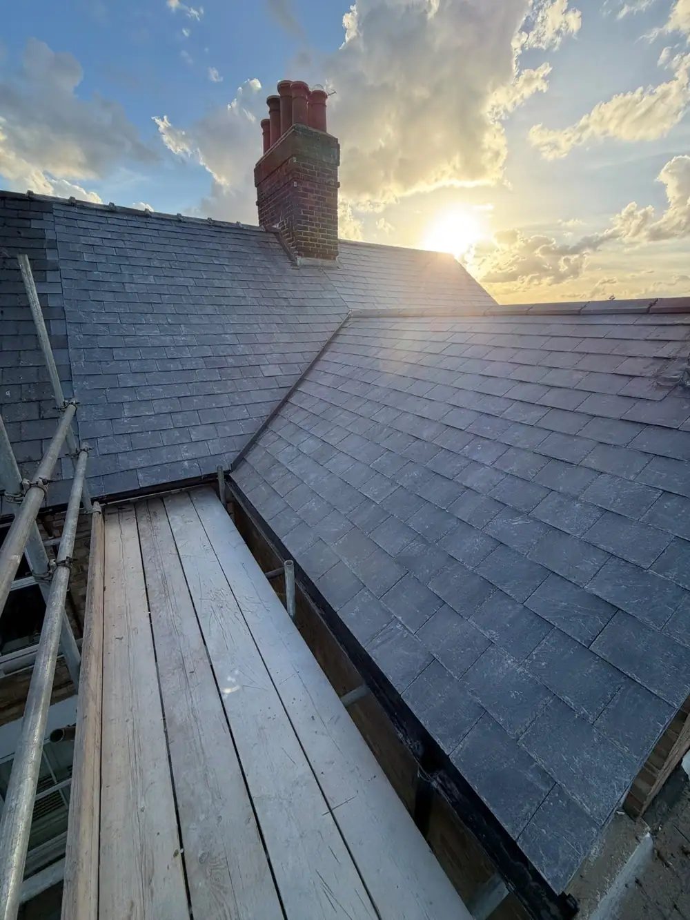 New slate roof and valley from the scaffold with the sun behind the chimney