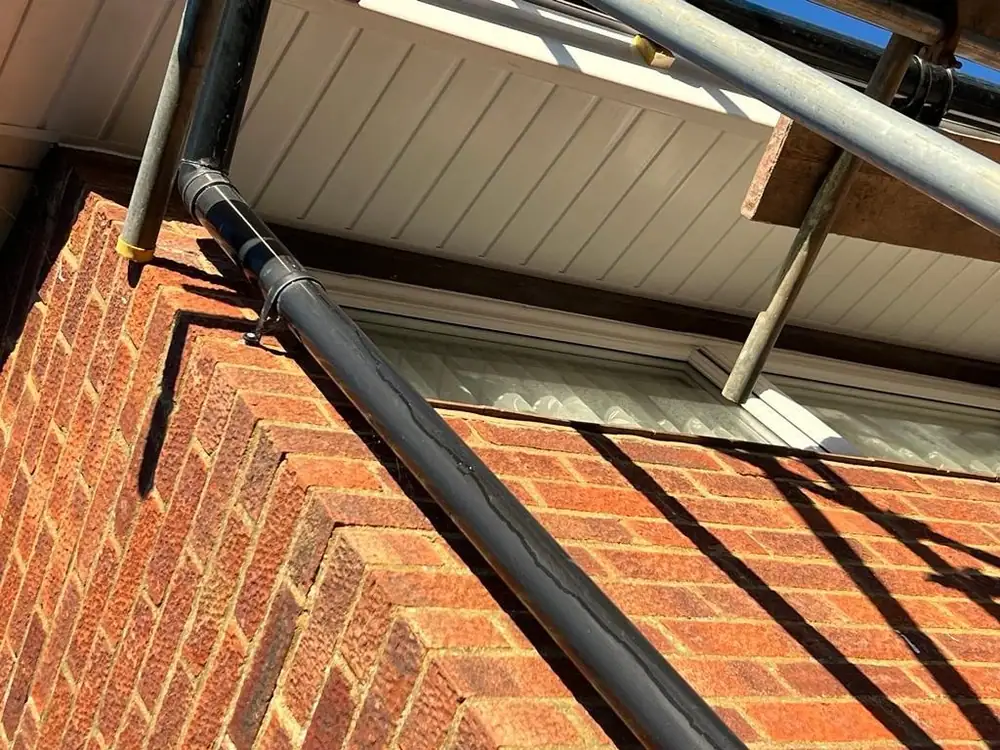 New white soffit and black downpipe on a brick corner