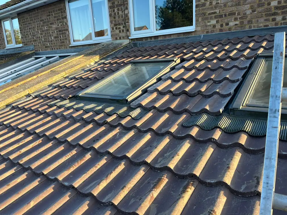 Roofers in Luton fitting new tiles around a roof window