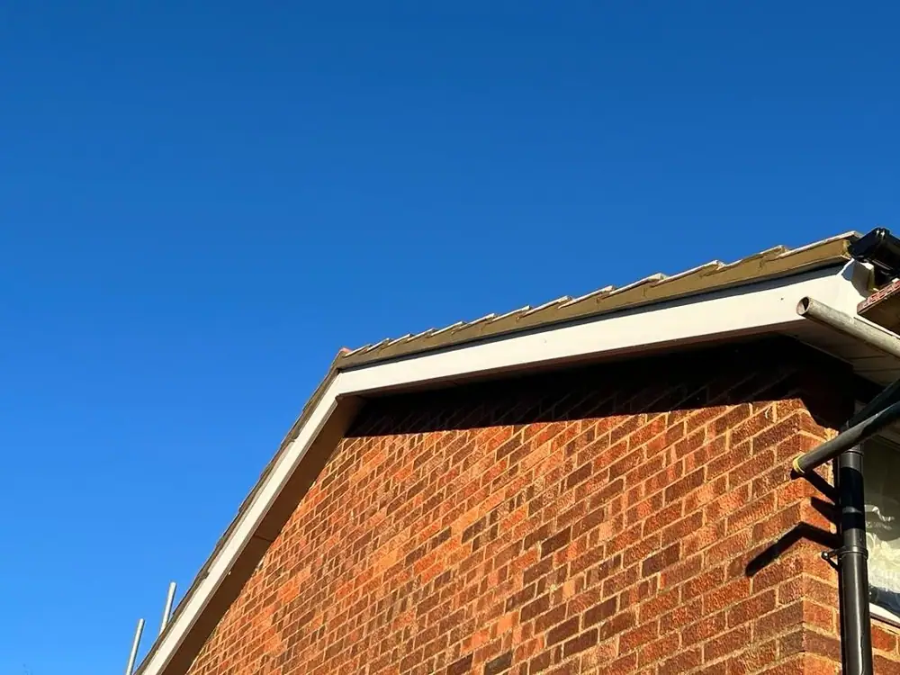 New white uPVC barge board on a red brick gable