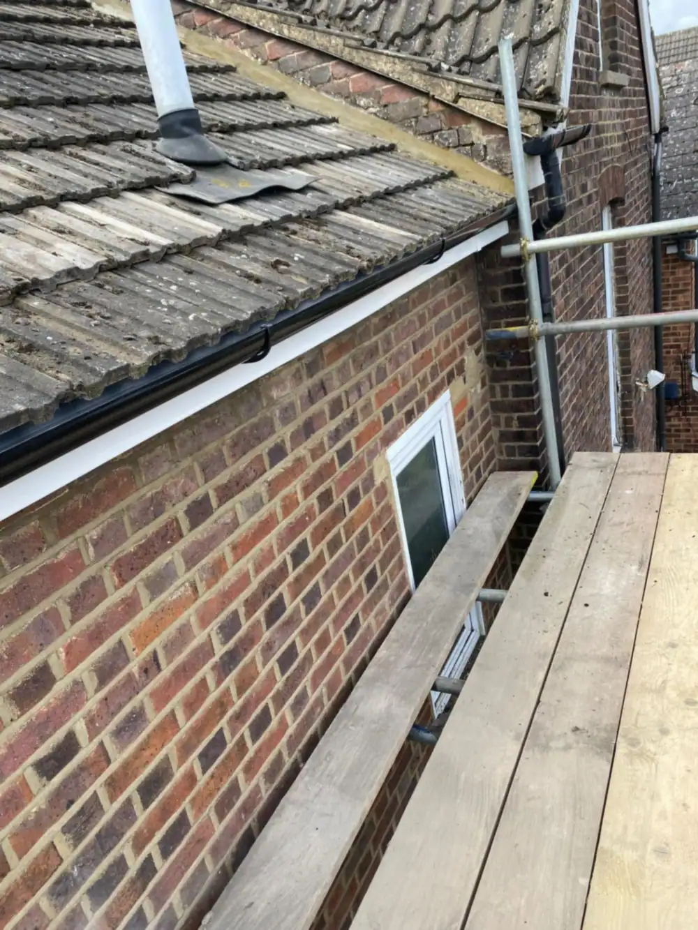 Old tile roof along a brick side wall from the scaffold