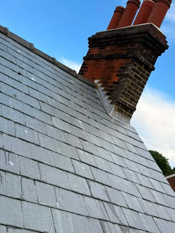 New slate roof running up to a brick chimney after slate roofing work