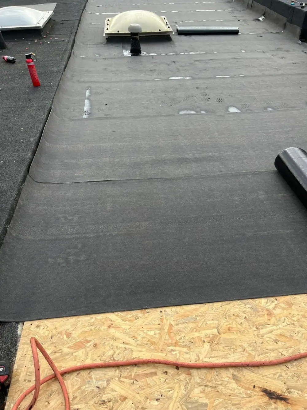 Torch-on felt base layer laid over a new OSB deck around a roof light