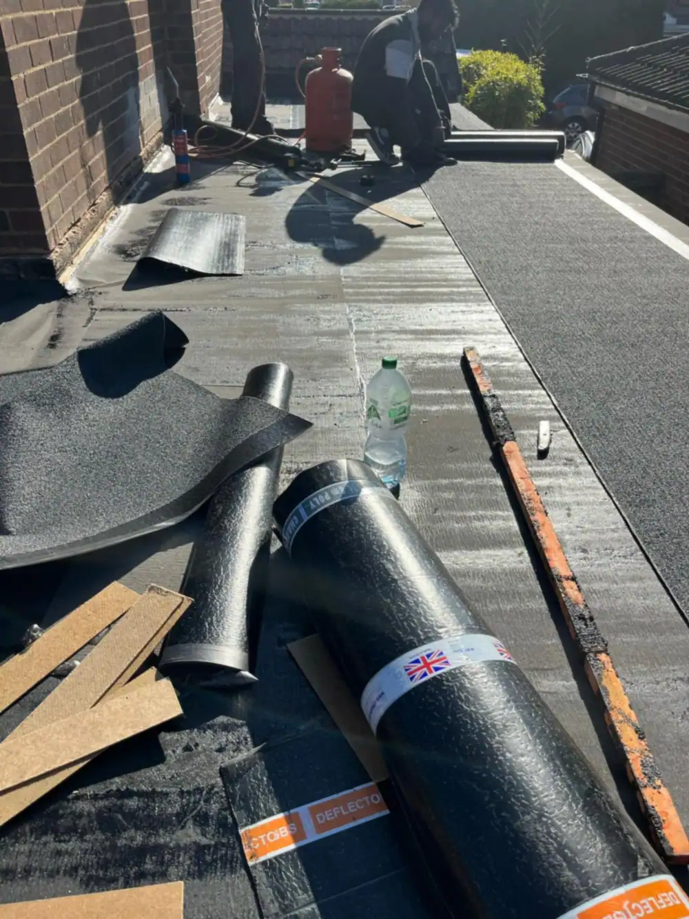 Rolls of torch-on felt on a flat roof mid job
